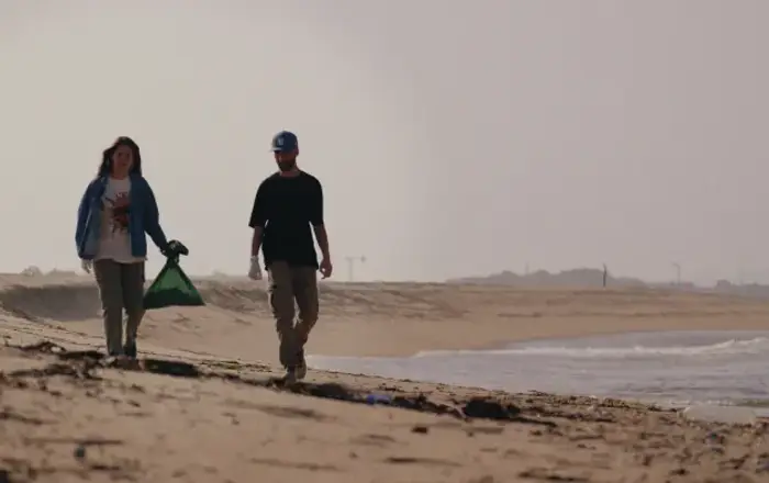 Two travellers collecting litter on a beach near Esposende