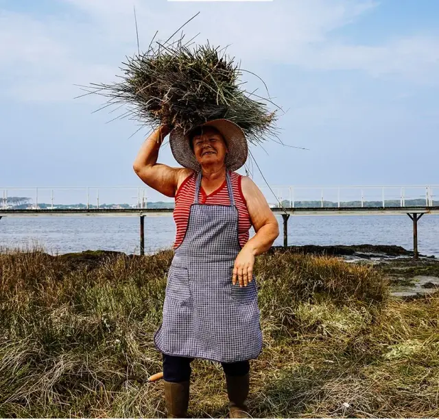 A local woman carrying a bundle of reeds on her head by the Cávado estuary